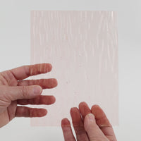 Video of the Blush Gentle Waves glass plate in transparent pink, 15x19cm, held up and tilted to show its pattern and transparency