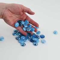 Video of turquoise mix glass nuggets in sky blue and turquoise shades with an iridescent sheen, 16–20 mm, picked up from a pile by hand and dropped back to show their size, round shape and shine