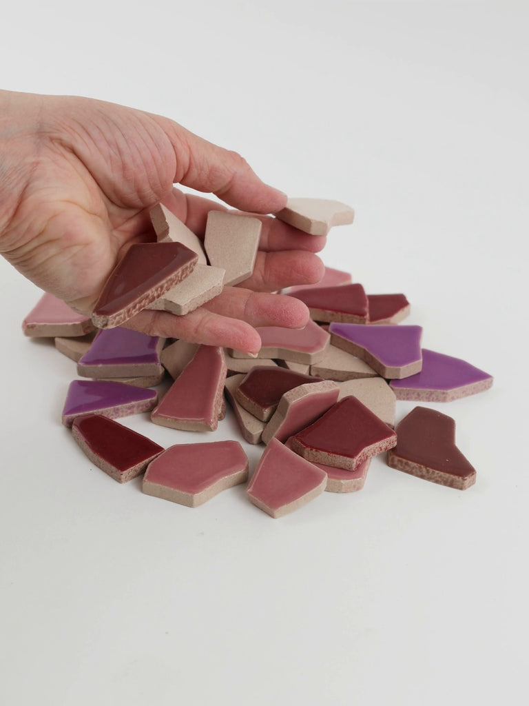 Video of Flip XL ceramic puzzle pieces in purple mix, opaque glazed porcelain, 20–60 mm, picked up from a pile by hand and dropped back to show their size, shapes and finish