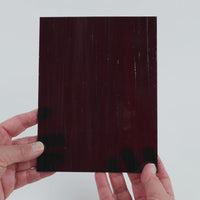 Video of the Plum Streaky glass plate in translucent purple, 15x19cm, held up and tilted to show its pattern and transparency