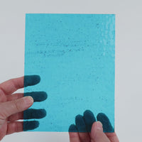 Video of the Pale Turquoise hammered glass plate in hammered transparent turquoise, 15x19cm, held up and tilted to show its pattern and transparency